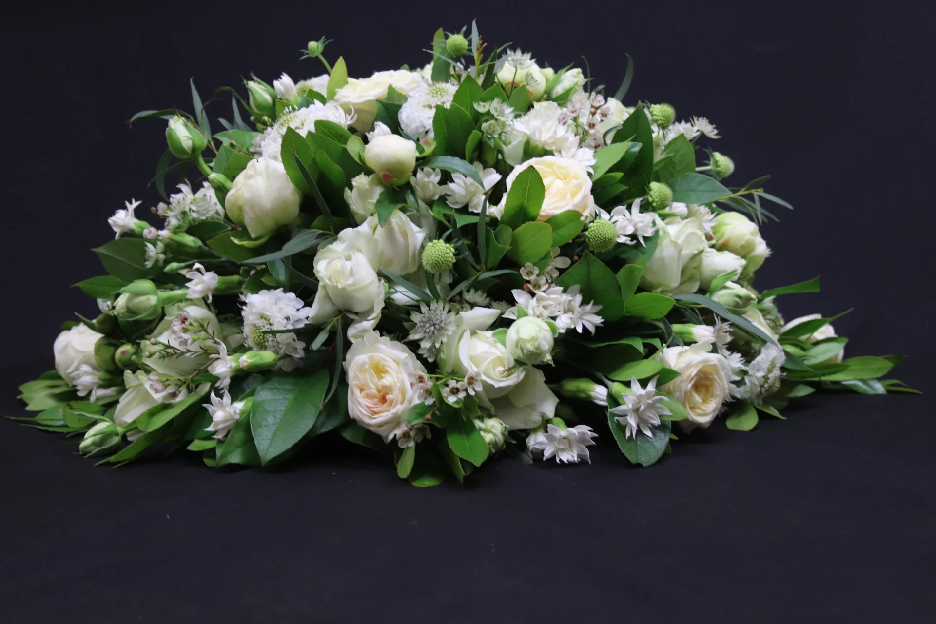 Rouwstuk White Tears. Een groot bloemstuk met verschillende witte bloemen, afgewerkt met groen. Gemaakt door Bloeibloemen.nl