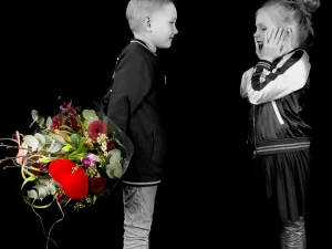 Een jongen die een meisje een boeket bloemen geeft van Bloeibloemen.nl. In het midden van het boeket zit een groot rood hart. Wij noemen dit ook wel het love bouquet