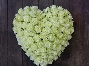 Rouwstuk Roses from the heart, een rouw bloemstuk op een kist witte rozen in de vorm van een hart, gemaakt door Bloeibloemen.nl