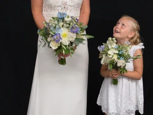 Little Blue bruidsboeket. Een bruid en een bruidsmeisje allebei met een bruidsboeket met witte en paarse bloemen in hun handen.