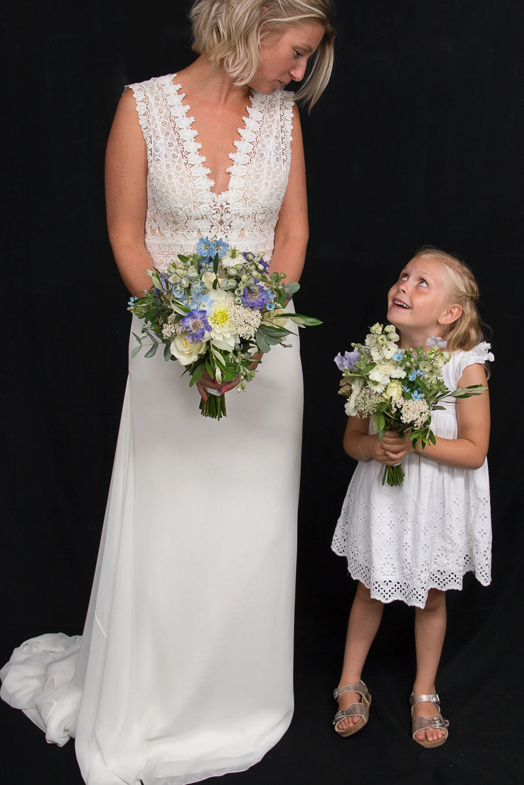 Little Blue bruidsboeket. Een bruid en een bruidsmeisje allebei met een bruidsboeket met witte en paarse bloemen in hun handen.