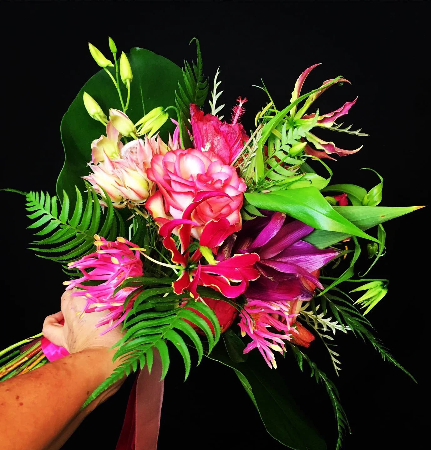 Een boeket bloemen met hele mooie, felle kleuren bloemen zoals roze, rood, geel en groen.