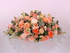 Rouw bloemstuk Peach love gemaakt voor een begrafenis. Dit rouwstuk heeft verschillende oranje, zachtroze en witte bloemen.