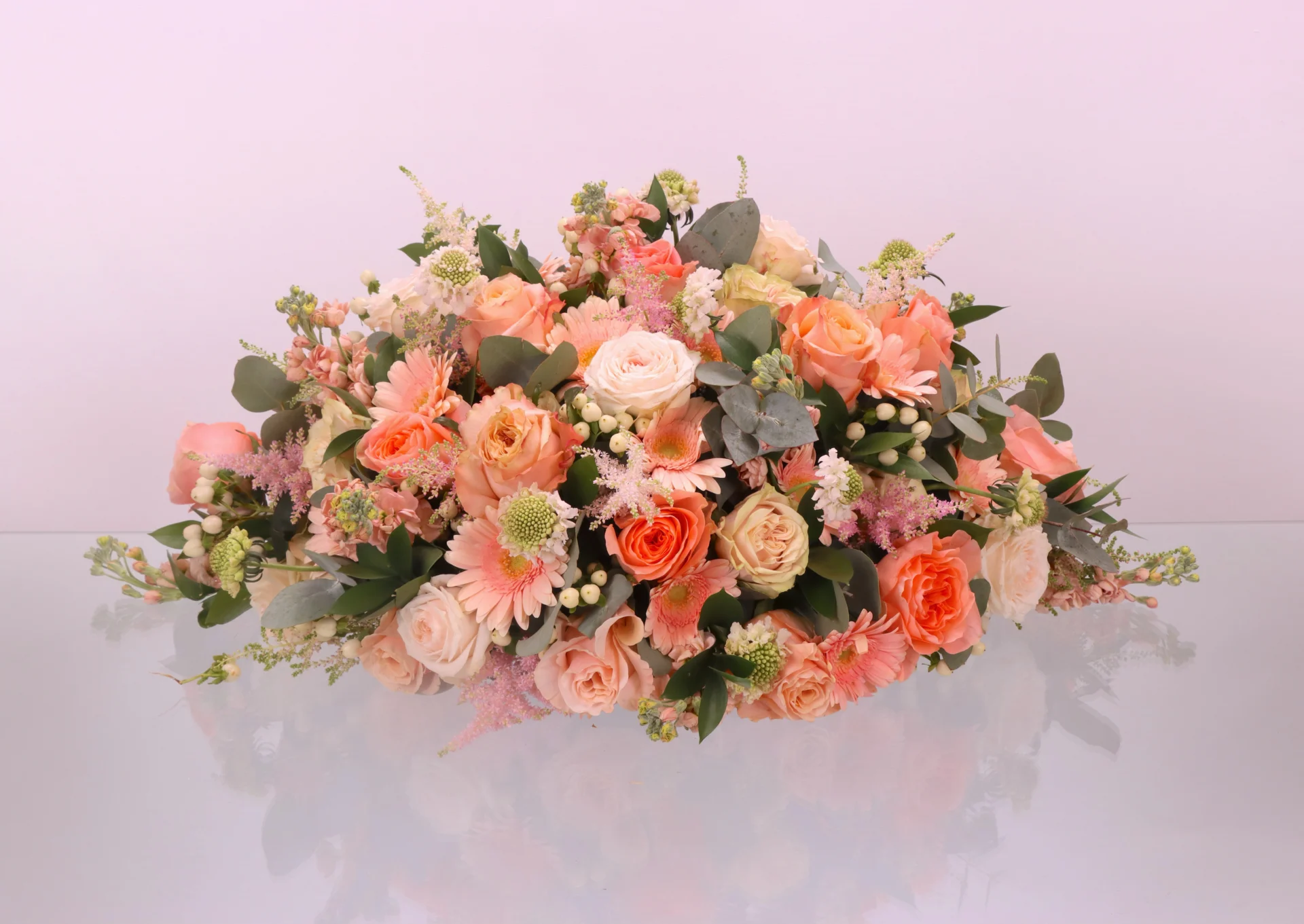 Rouw bloemstuk Peach love gemaakt voor een begrafenis. Dit rouwstuk heeft verschillende oranje, zachtroze en witte bloemen.